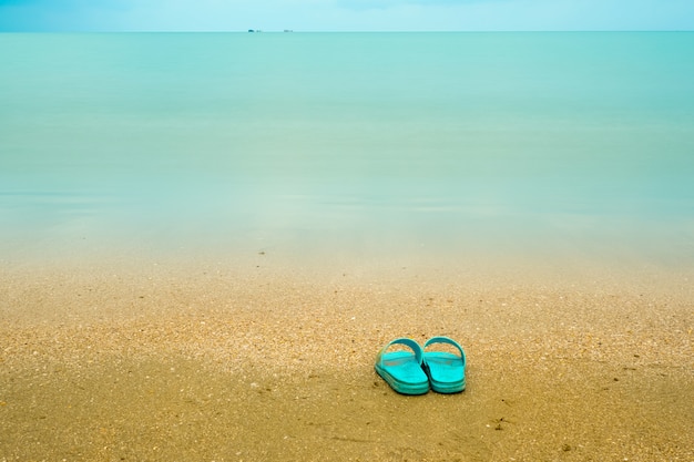 Blauwe sandalen op het strand.