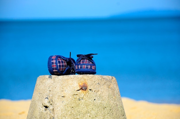 Blauwe schoenen voor pasgeboren babypantoffel op het strand en het zeezand hieronder Schoen met geruit en plaid.