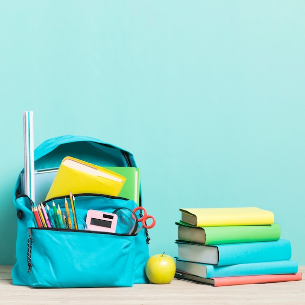Foto blauwe schoolrugzak met benodigdheden en schoolboeken