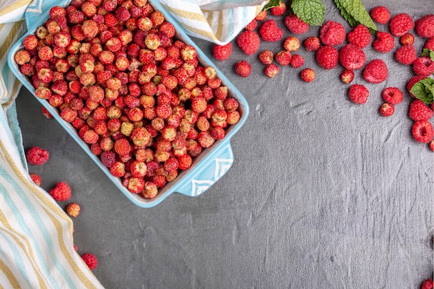 Blauwe schotel van wilde aardbeien met bessen en frambozen en gestreepte kithen handdoek