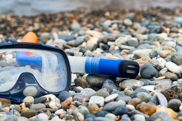 Blauwe snorkel en masker om te duiken op het kiezelstrand.