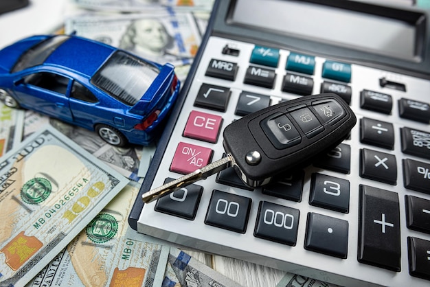 Blauwe speelgoedauto met echte sleutelscalculator over Amerikaanse dollarbankbiljetten