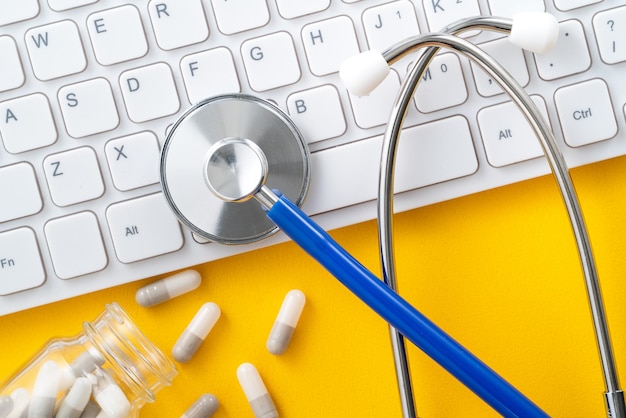 Blauwe stethoscoop met computertoetsenbord en capsulepil medisch ontwerpconcept
