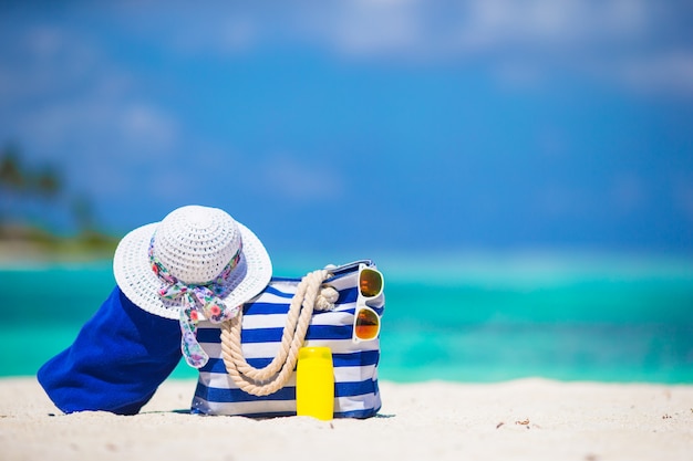 Blauwe streepzak en handdoek, strooien witte hoed, zonnebril, zonneschermfles op exotisch strand