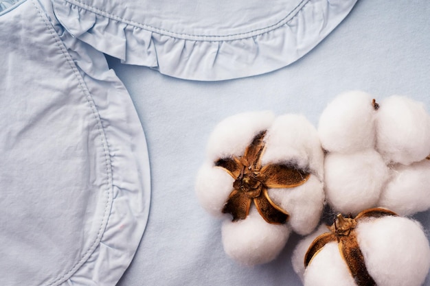 Blauwe T-shirt met een kraag en katoenen bloemen close-up Het concept van kleding gemaakt van natuurlijke stoffen Mooie merkkleding achtergrond