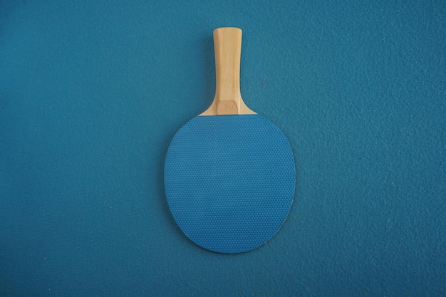 Blauwe tafeltennis- of pingpongracket ligt ondersteboven op blauwe achtergrond met een close-upweergave van bovenaf Spel voor vrije tijd Sportuitrusting