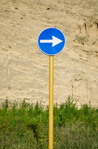 Blauwe verkeersbord met pijl op verweerde oude muur