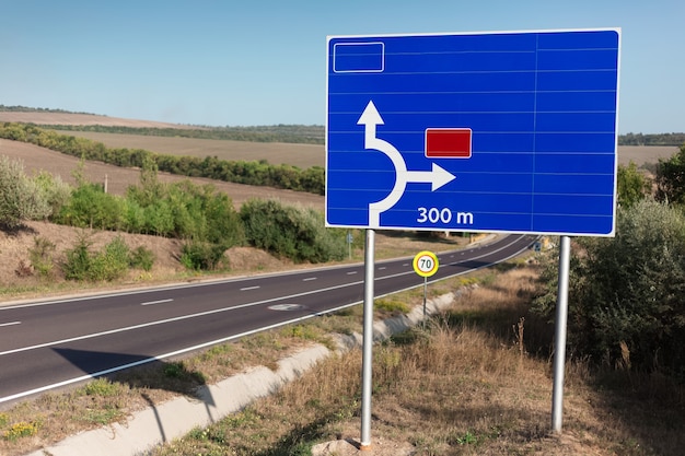 Blauwe verkeersbord met richting in de buurt van snelweg.