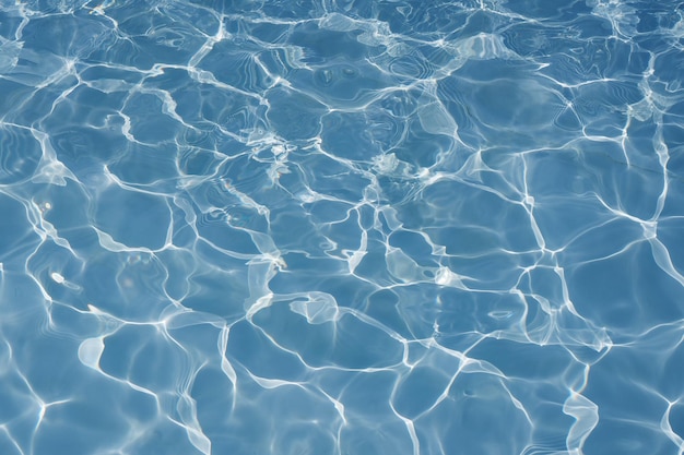 Blauwe waterspiegel met helder zonlicht reflecties water in zwembad achtergrond