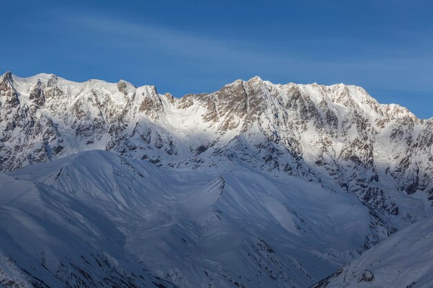 Blauwe winter bewolkte lucht boven een berg met negen toppen Sjchara, het centrale deel van de Grotere Kaukasus-bergketen Boven Svaneti Georgië Europa