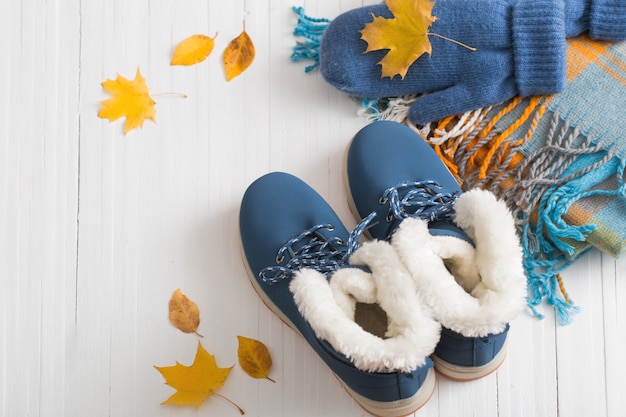 Blauwe winterschoenen en handschoenen op witte houten achtergrond