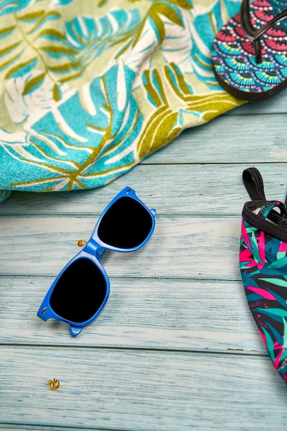 Blauwe zonnebril, flip-flops, zwembroek en strandhanddoek.