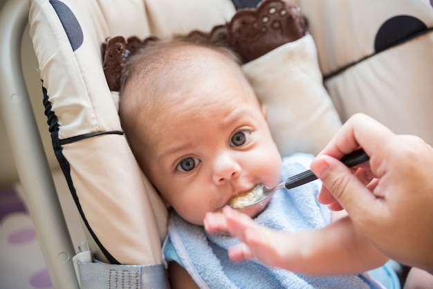 Blauwogige babyjongen die - in babywandelwagen eet