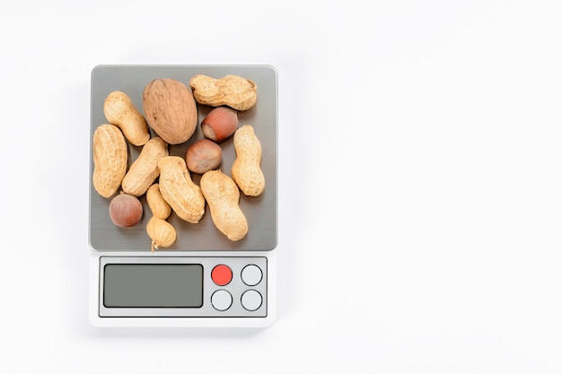Foto miscela di noci su bilance elettroniche con sfondo bianco. concetto di dieta e perdita di peso.