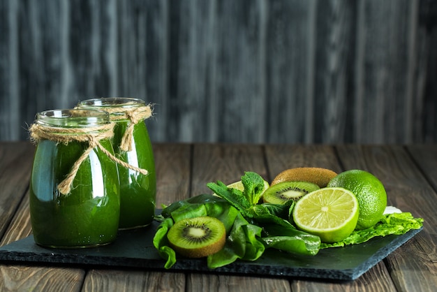 Blended green smoothie with ingredients on the stone board, wood