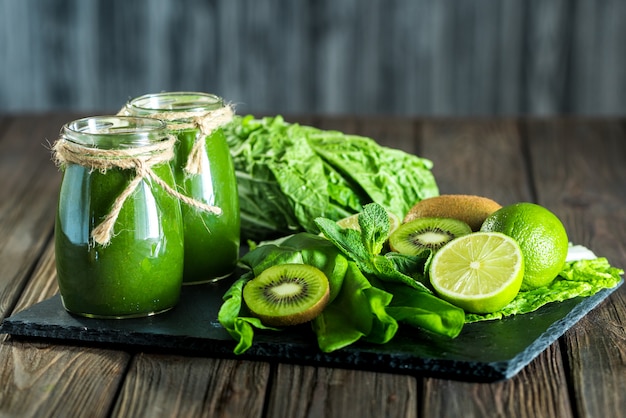 Blended green smoothie with ingredients on the stone board, wood