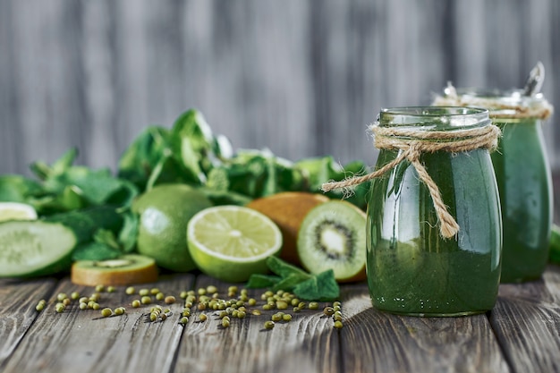 Blended green smoothie with ingredients on the stone board, wooden table selective focus