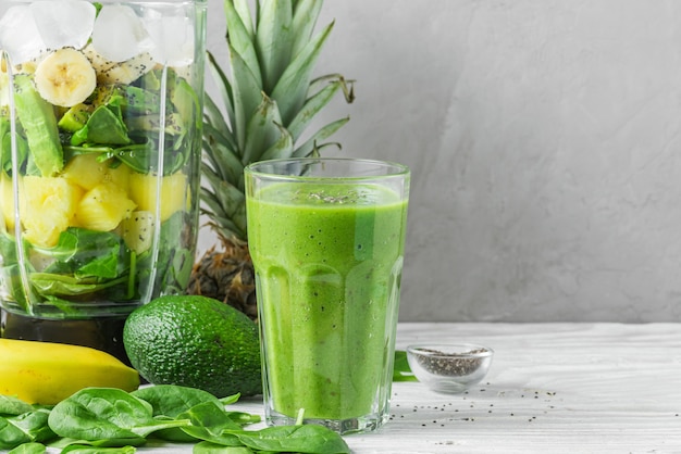 Blender for making smoothie and glass with green healthy smoothie detox made of spinach, pineapple, avocado