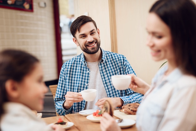 カフェテリアでケーキを食べて幸せな家族を祝福します。