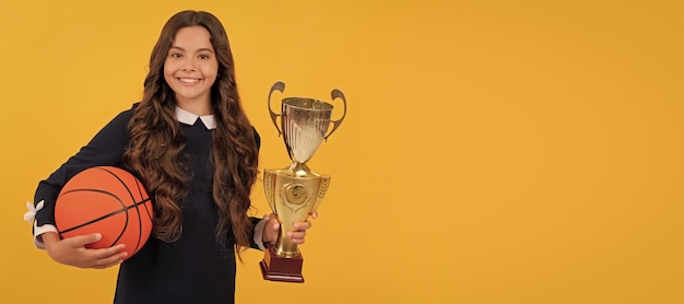 Blij kind houdt basketbalbal en kampioensbeker op gele achtergrondoverwinning Horizontale poster