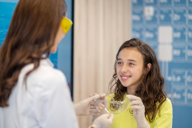 Blij meisje dat een veiligheidsbril van de leraar neemt