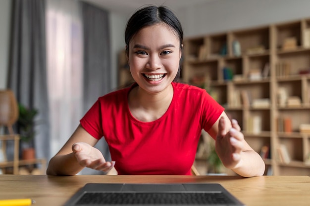Blij opgewonden jonge Aziatische vrouwelijke student verheugt zich en kijkt naar het computerscherm heeft online chat in het interieur van de kamer
