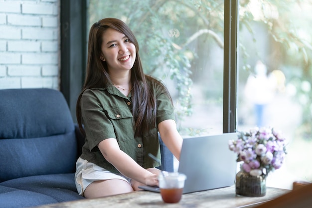 Blij van aziatische freelance mensen zakelijke vrouwelijke casual werken met laptopcomputer met koffiekopje en smartphone in coffeeshop zoals het backgroundcommunication concept