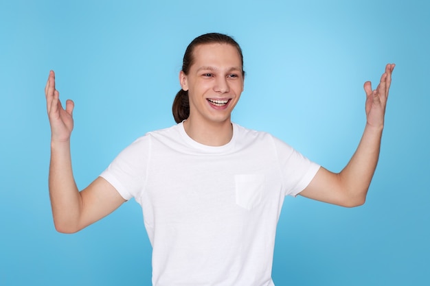 Blij verrast jonge knappe man in t-shirt geïsoleerd op blauwe achtergrond. Menselijke emoties, gezichtsuitdrukkingen