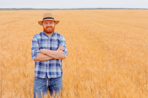 Blije boer Staande plant in zijn tarweveld Boeren boer die met vaardigheid en zorg tarwe in het veld cultiveert