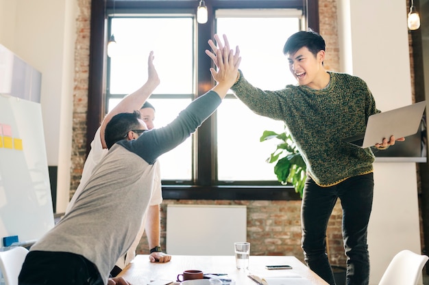 Blije diverse collega's in een startend bedrijf die een high five doen