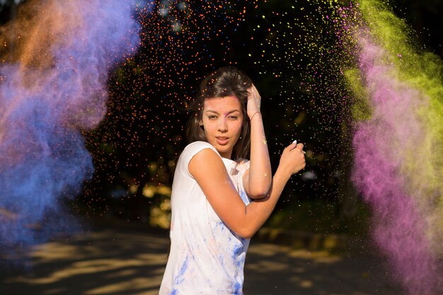 Foto blije donkerbruine aziatische vrouw die met lang haar met holi-poeder speelt