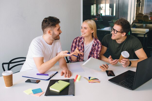 Blije en positieve studenten zitten aan tafel en praten