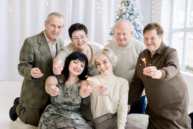 Blije familie van drie generaties die sterretjes houden die Kerstboom zitten