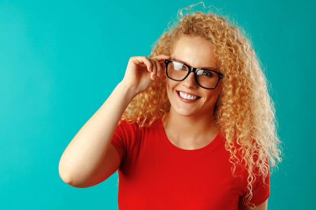 Blije jonge krullende vrouw die in glazen glimlachen