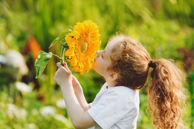 Blije kind geur zonnebloem genieten van de natuur in zonnige zomerdag.