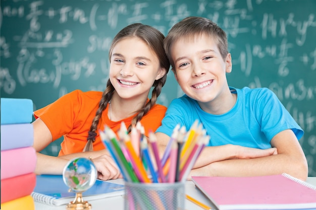 Blije kinderen zitten tijdens de les aan tafel