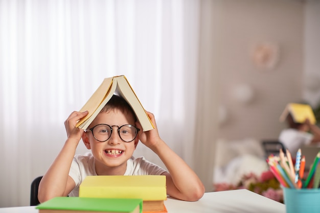 Blije kleine jongenszitting bij de lijst met potloden en handboeken.