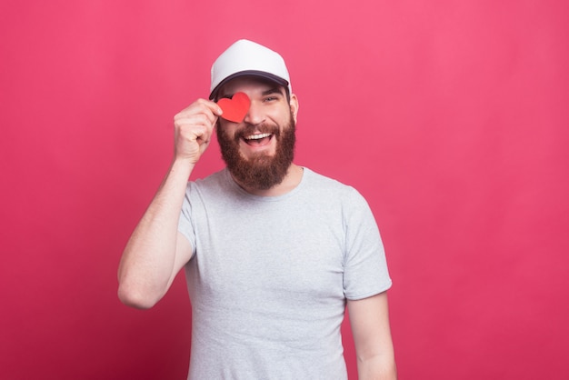 Blije knappe man met rood papier hart over ogen