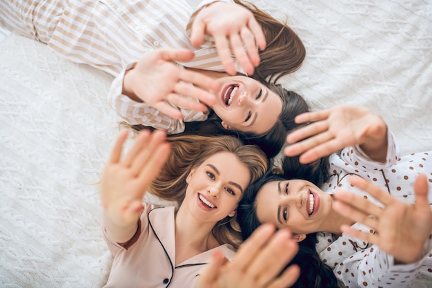 Blije meiden. Drie meisje liggend in bed glimlachend en op zoek gelukkig