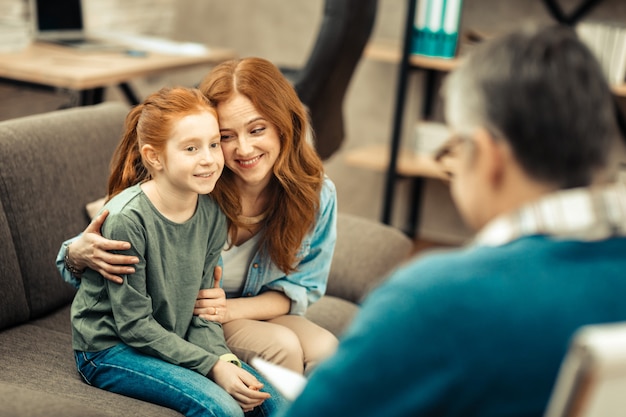 Blije moeder. Opgetogen positieve vrouw die naar haar dochter lacht terwijl ze in een goed humeur is