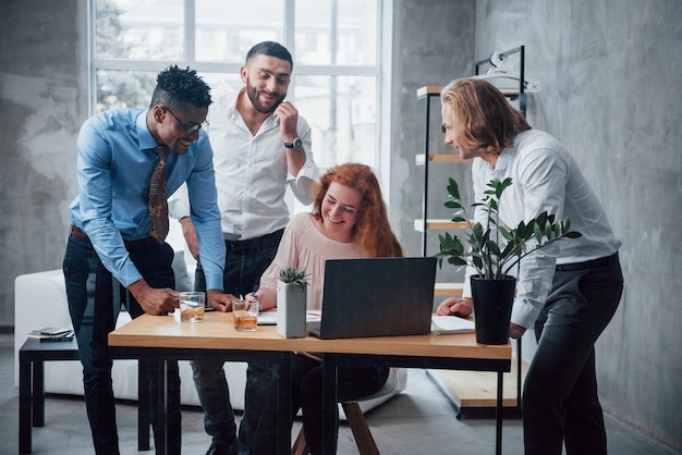 Blije opwinding. Jong commercieel team dat aan een project met laptop bij lijst en het glimlachen werkt