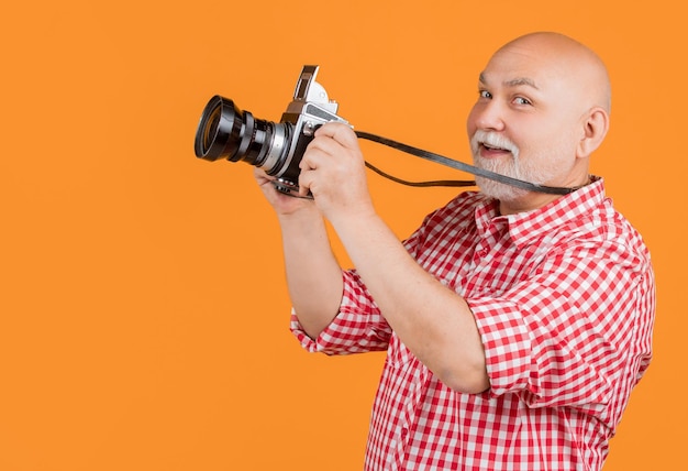 Blije oude man met retro fotocamera op gele baqckground