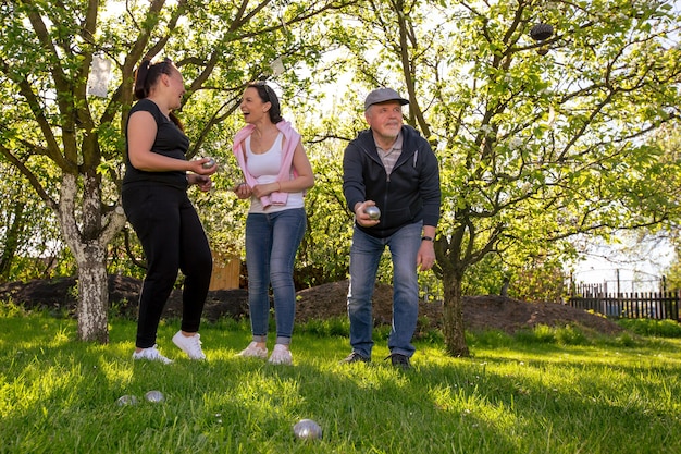 Blije positieve glimlachende familie die Franse traditionele petanque speelt in een tuin buiten tijdens een mooie zomerdag die geniet van vrije tijd