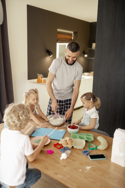 Foto blije positieve man die een omelet voor zijn kinderen klaarmaakt