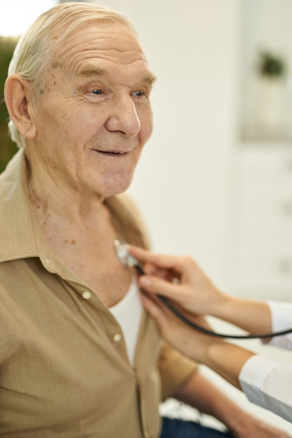 Foto blije senior man die naar zijn longen luistert door dokter