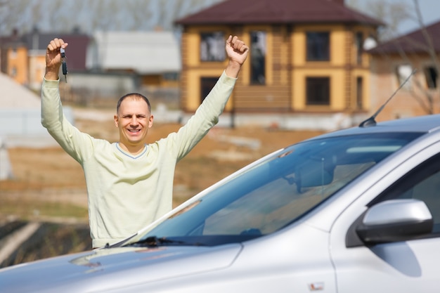 Foto blije succesvolle man in de auto achtergrond cottage