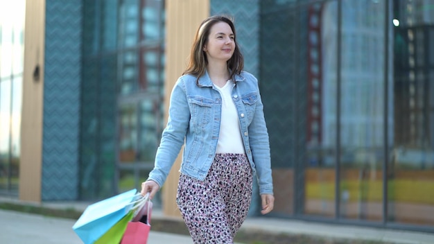 Foto blije tevreden vrouw gaat na het winkelen een jong meisje houdt tassen van verschillende kleuren in haar handen