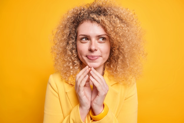 Blije vrouw met krullend haar heeft slechte perfecte plannen