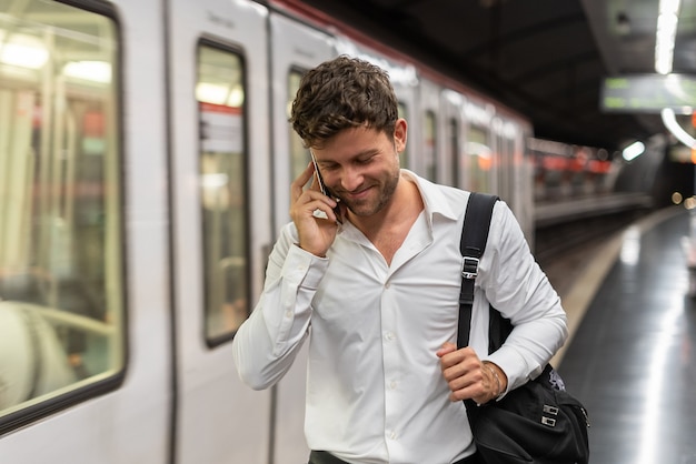 Blije zakenman die smartphonegesprek op station heeft