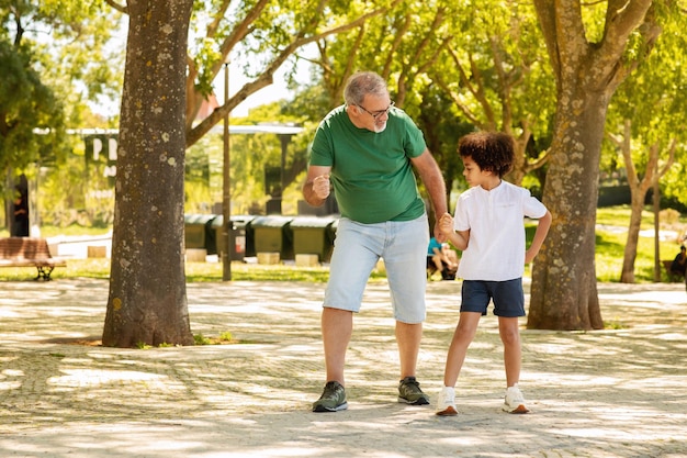 Blije zwarte kleine jongen en man met baard spelen rust in parkwedstrijd buiten